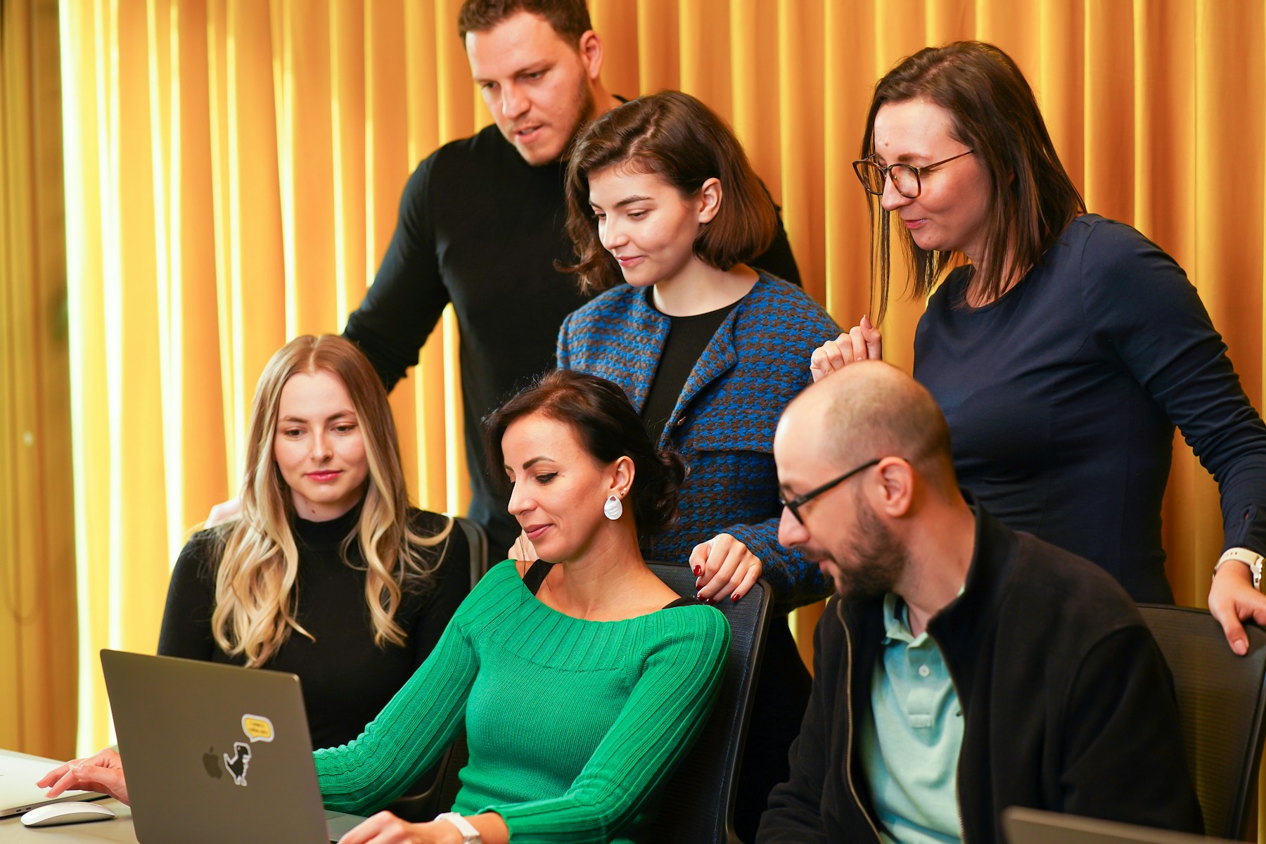 Professionals collaborating around a laptop
